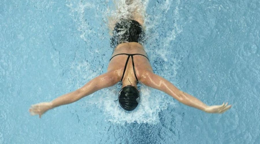 Woman swimming butterfly shot from above.
