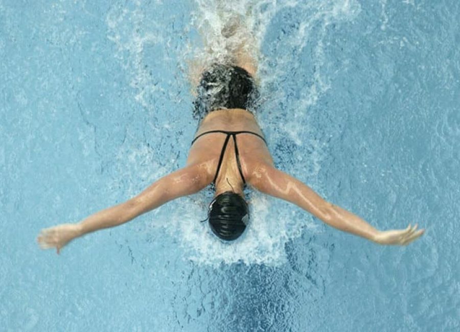 Woman swimming butterfly shot from above.